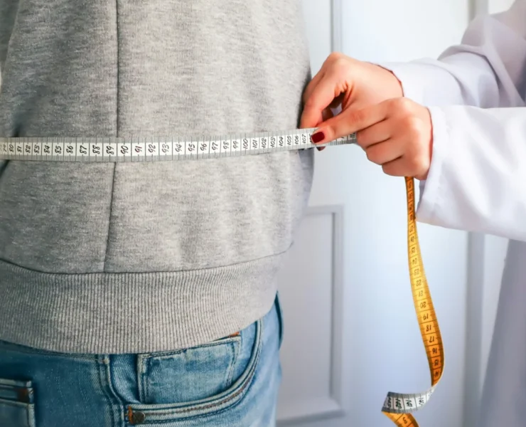 A doctor measuring a patient's waist.