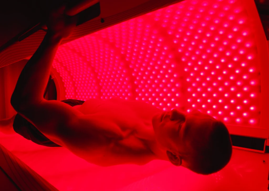 man lies down in a red light therapy bed