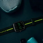 A person standing showing their sneakers and a watch in a gym.