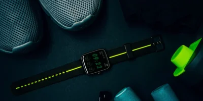 A person standing showing their sneakers and a watch in a gym.