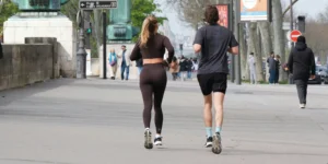 A couple running in the street and wearing activewear.