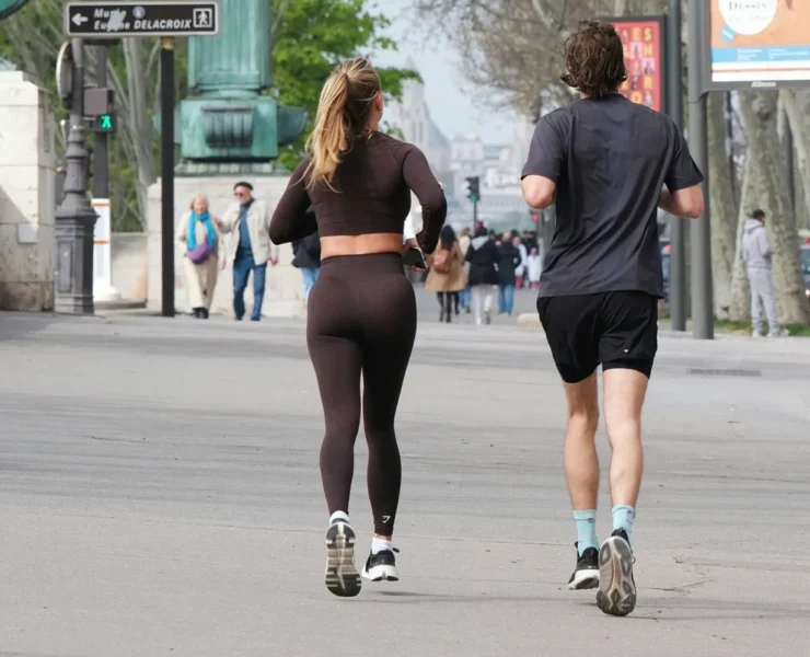 A couple running in the street and wearing activewear.