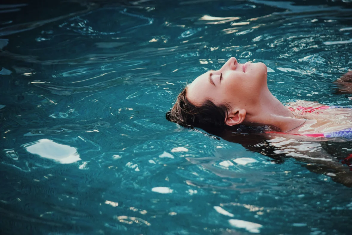 a woman relaxing/floating in an indoor pool