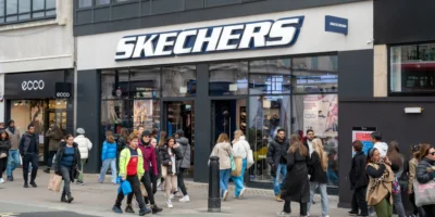 The exterior of a Skechers store with people milling about outside and in front of the store.