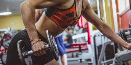 A woman strength training in the gym with a free weight.