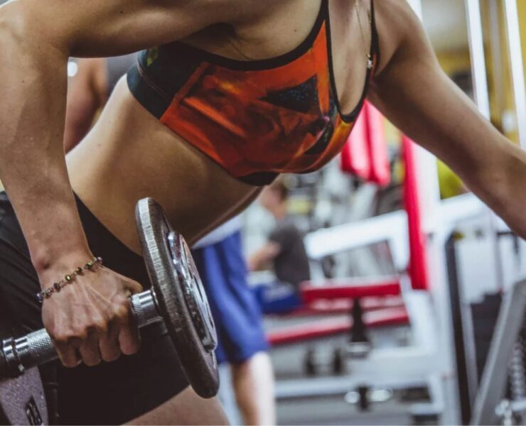 A woman strength training in the gym with a free weight.