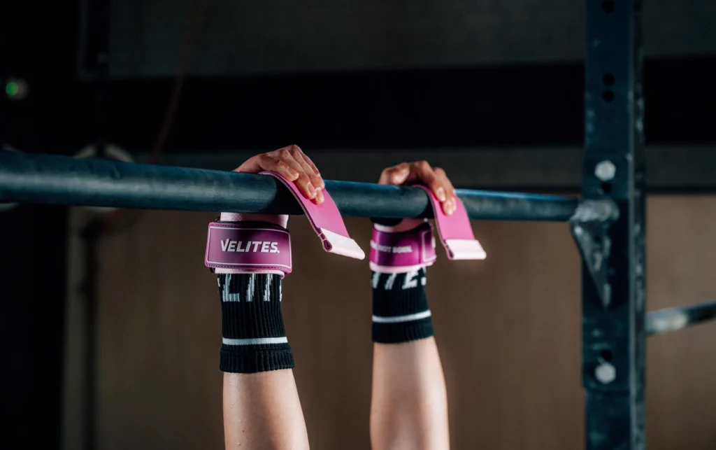 woman hangs on a pull up bar with Velites straps
