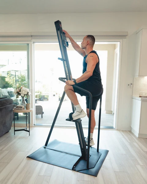 A man using the VersaClimber in a living room setting.