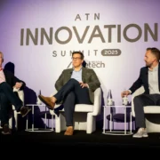 three male panelists speak on stage during the ATN Innovation Summit