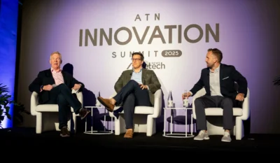 three male panelists speak on stage during the ATN Innovation Summit
