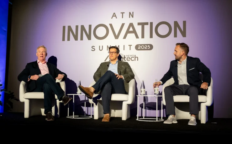 three male panelists speak on stage during the ATN Innovation Summit