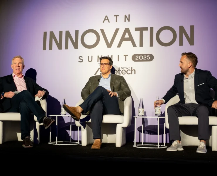 three male panelists speak on stage during the ATN Innovation Summit