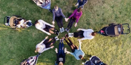 A group of women in a circle with strollers and babies.