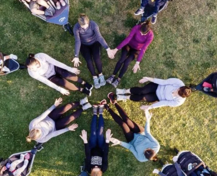 A group of women in a circle with strollers and babies.