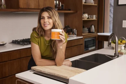 Marisa Tomei holding a jar of Terra Mare in a kitchen.