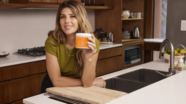 Marisa Tomei holding a jar of Terra Mare in a kitchen.