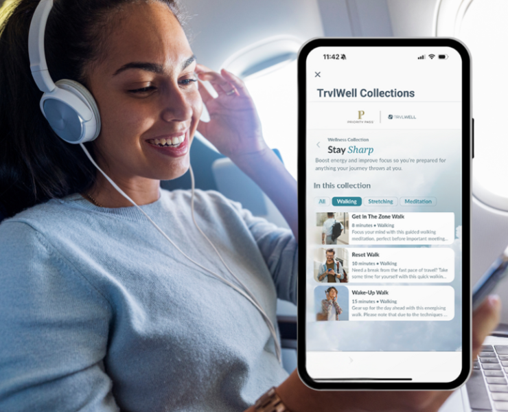 A woman on a plan looking at her phone and wearing headphones.
