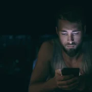 anxious young man doom-scrolls on his phone