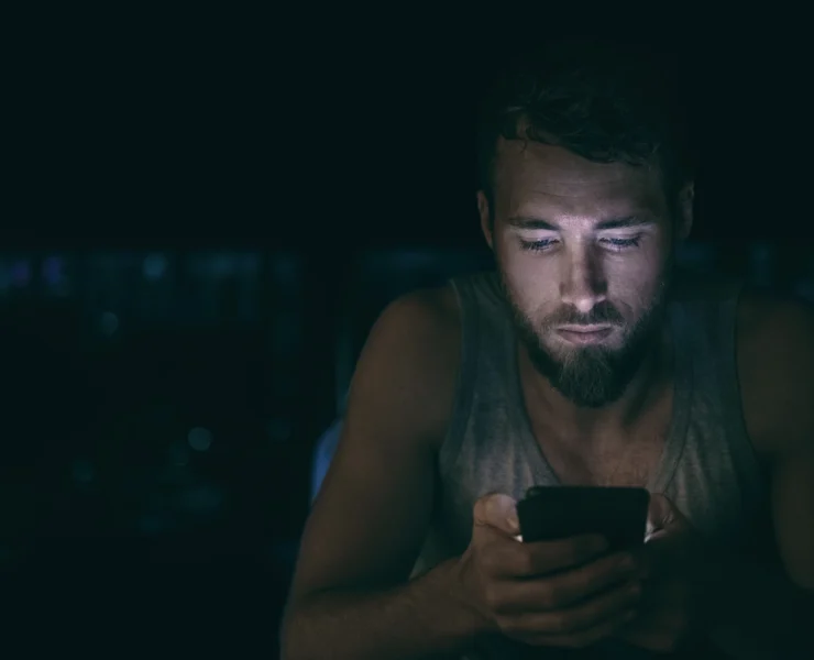 anxious young man doom-scrolls on his phone