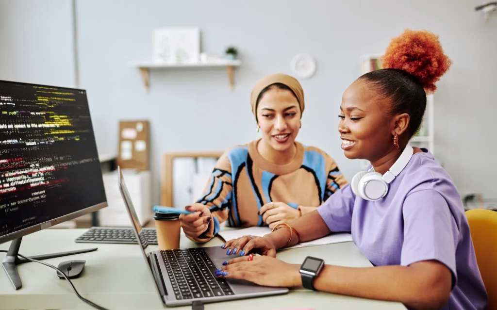 two Gen Z women work on a laptop