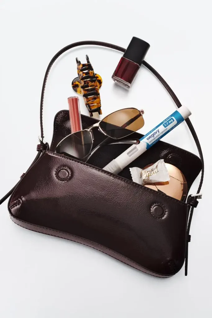 A woman's bag with items in it, including a GLP-1 shot.