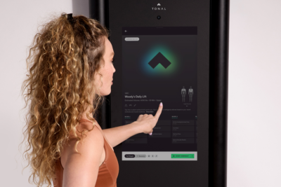 woman touches the screen on the Tonal 2 machine