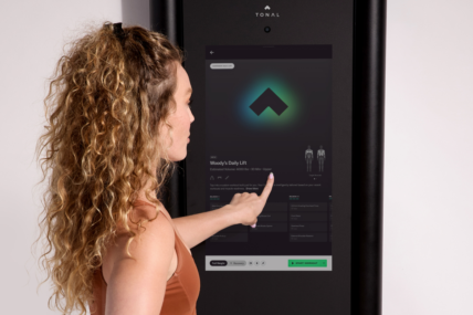 woman touches the screen on the Tonal 2 machine