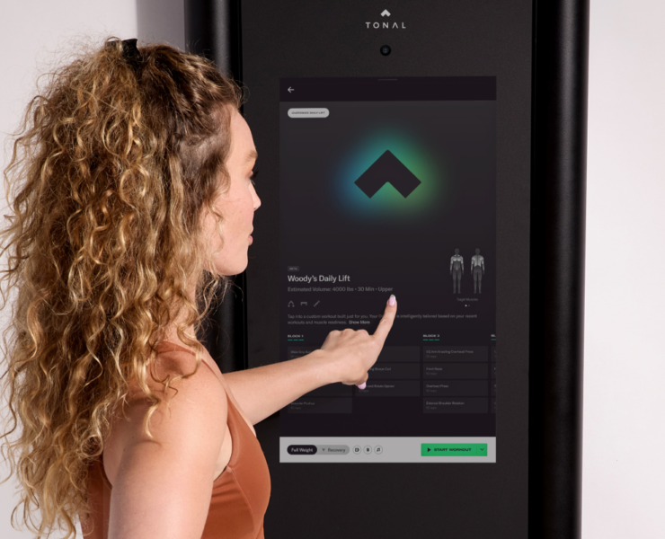woman touches the screen on the Tonal 2 machine