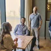 a group of people talk together in a room overlooking the ocean