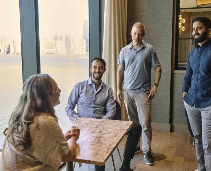 a group of people talk together in a room overlooking the ocean