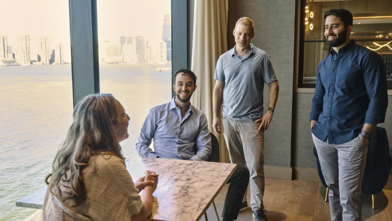 a group of people talk together in a room overlooking the ocean