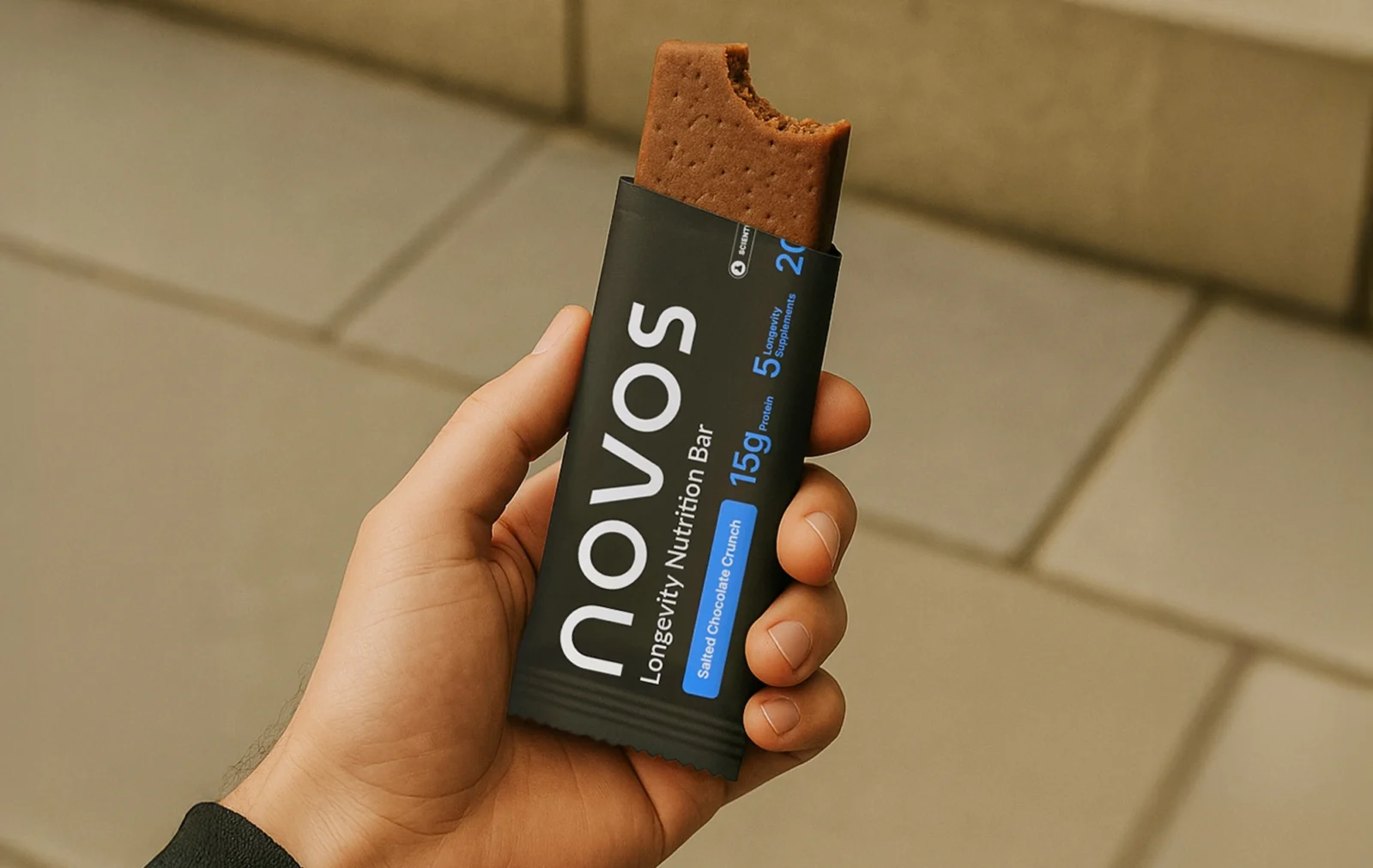 man holds a Novos chocolate functional longevity bar