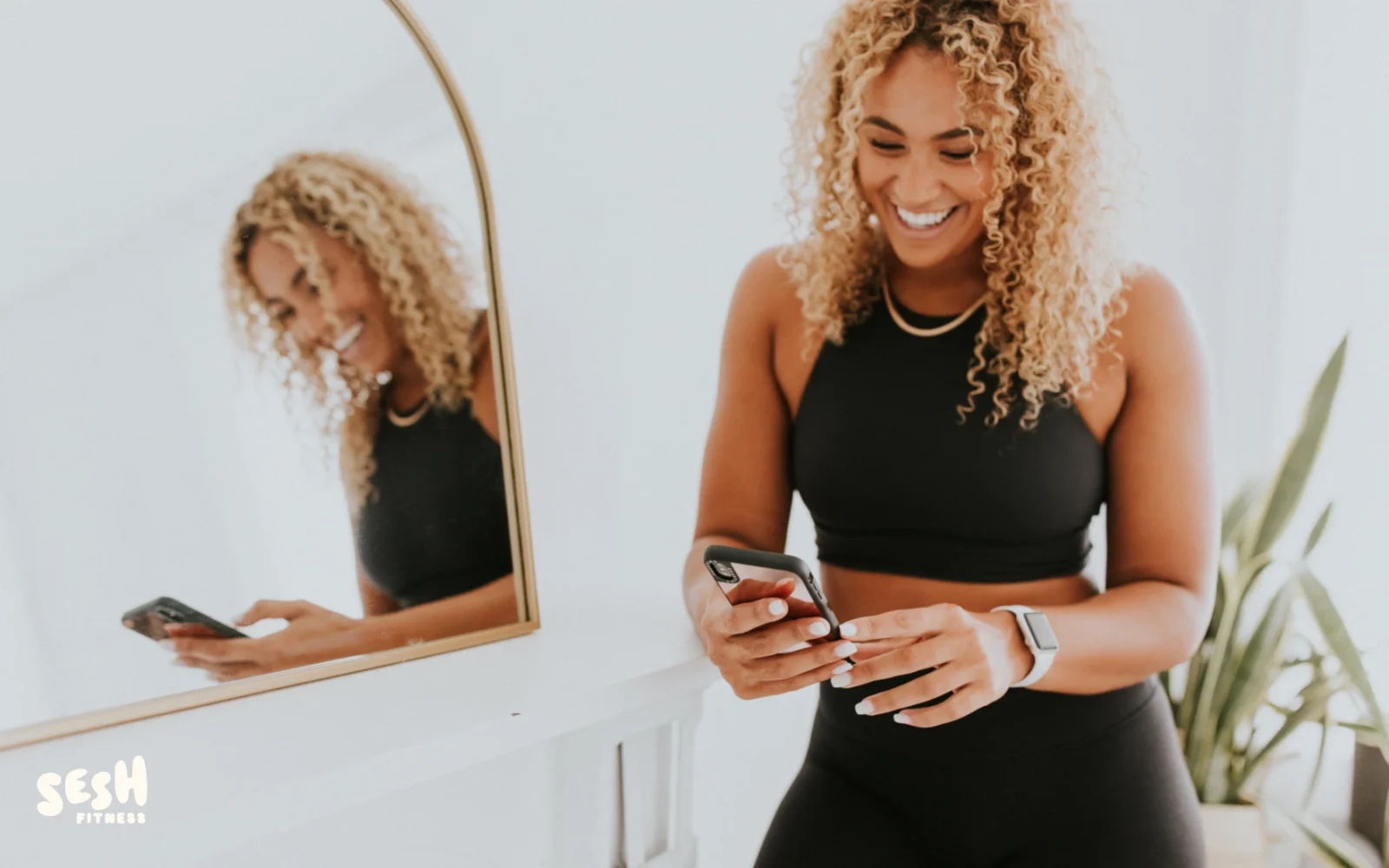 A woman looking at her phone in front of a mirror.