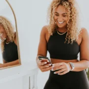 A woman looking at her phone in front of a mirror.