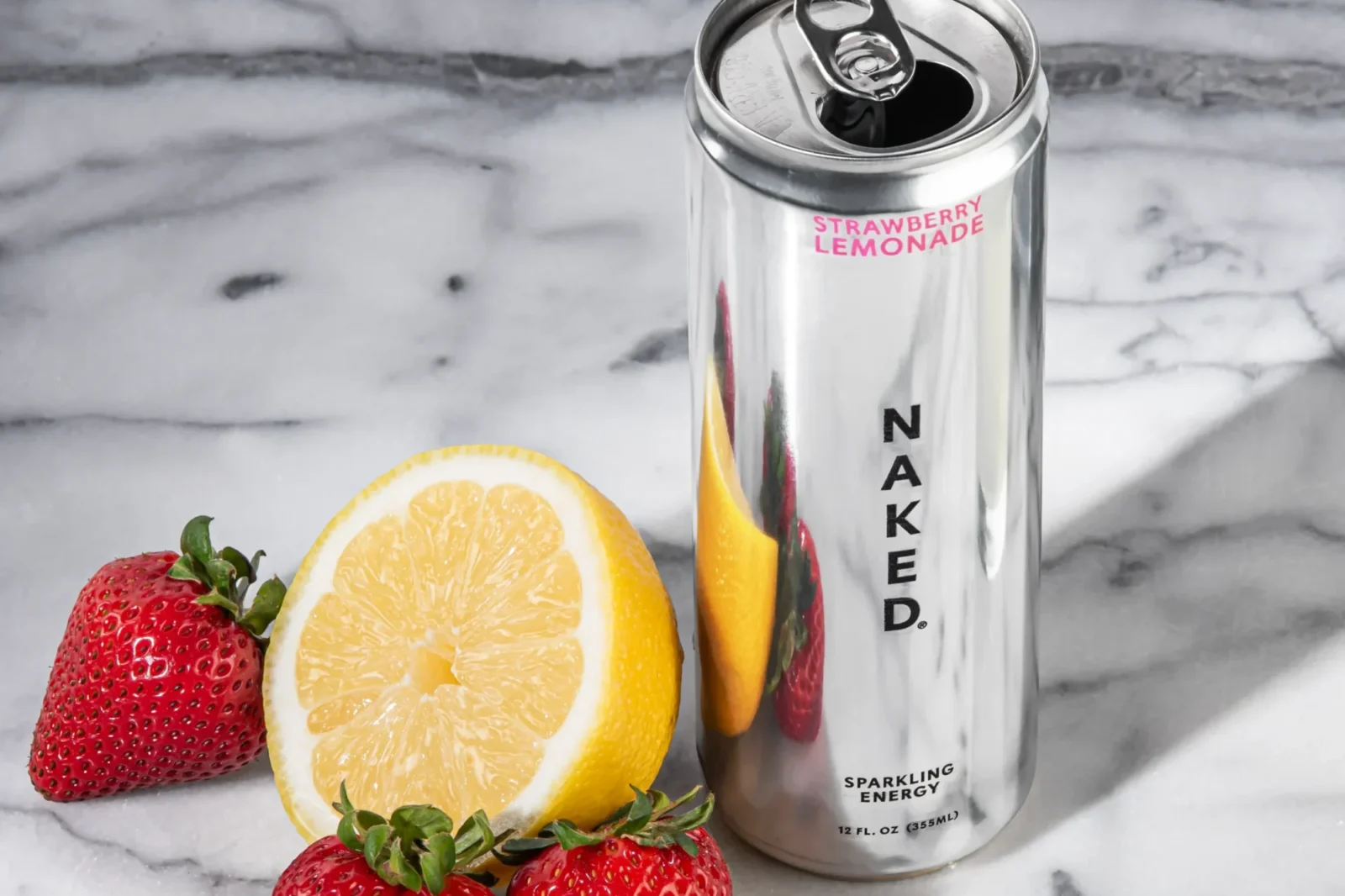 a can of Naked Sparking Energy alongside a lemon and strawberries.