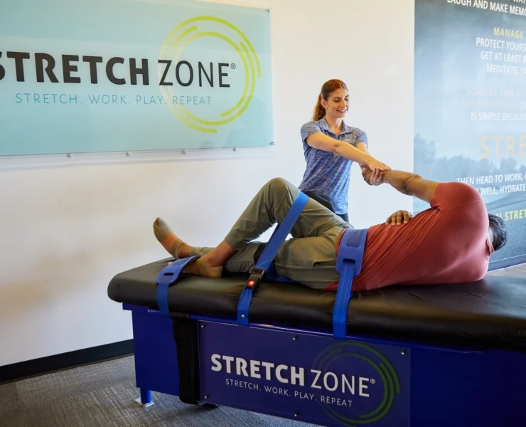 woman stretches a male client at a Stretch Zone