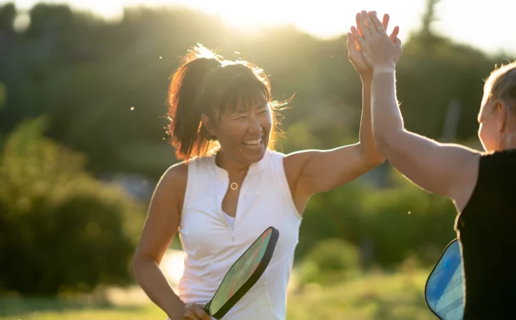 two people high-fiving with a pickleball paddle in a woman's hand