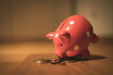 A pink piggy bank and a pile of coins