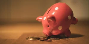 A pink piggy bank and a pile of coins