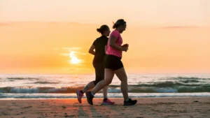 two women running on the beach during the sunset