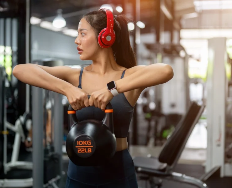 woman work out with a kettlebell and headphones on