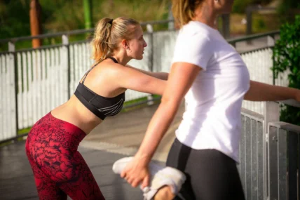 Two women stretching during a run.