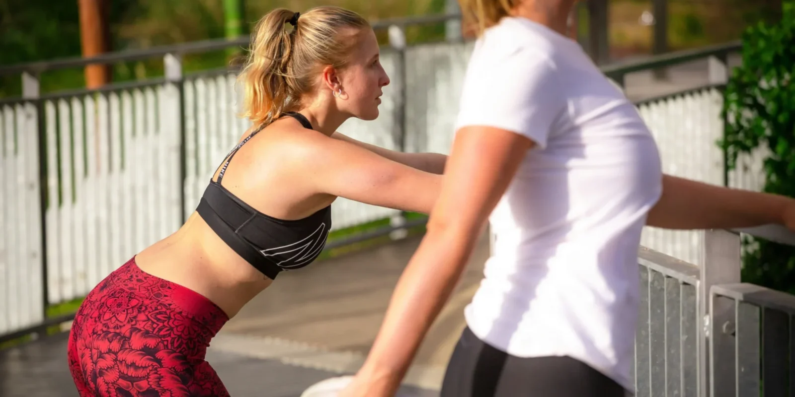 Two women stretching during a run.
