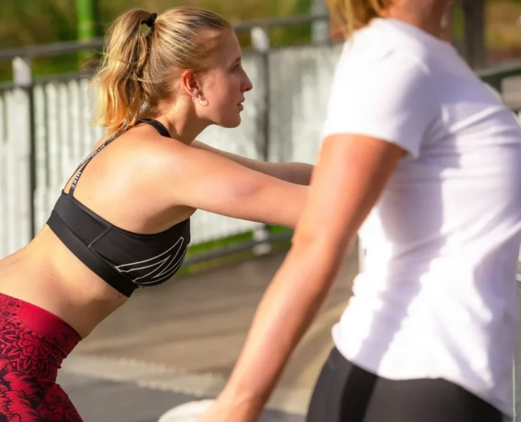 Two women stretching during a run.