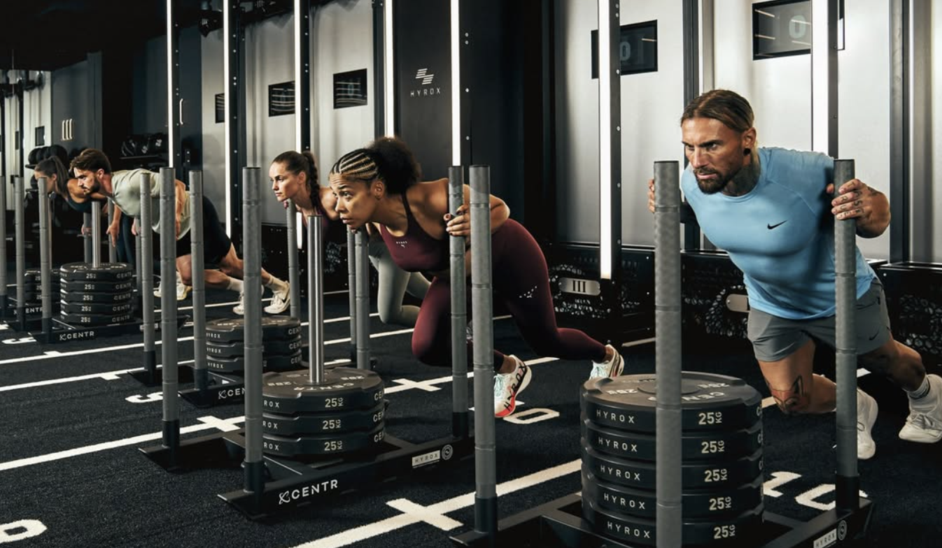 people push weight sleds inside a Hyrox training facility