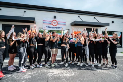 people pose for a photo outside of a Fly Dance Fitness location