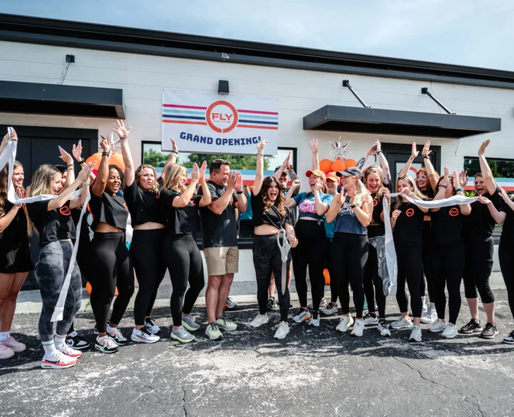 people pose for a photo outside of a Fly Dance Fitness location