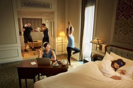 woman sleeps inside her hotel room bed while others workout