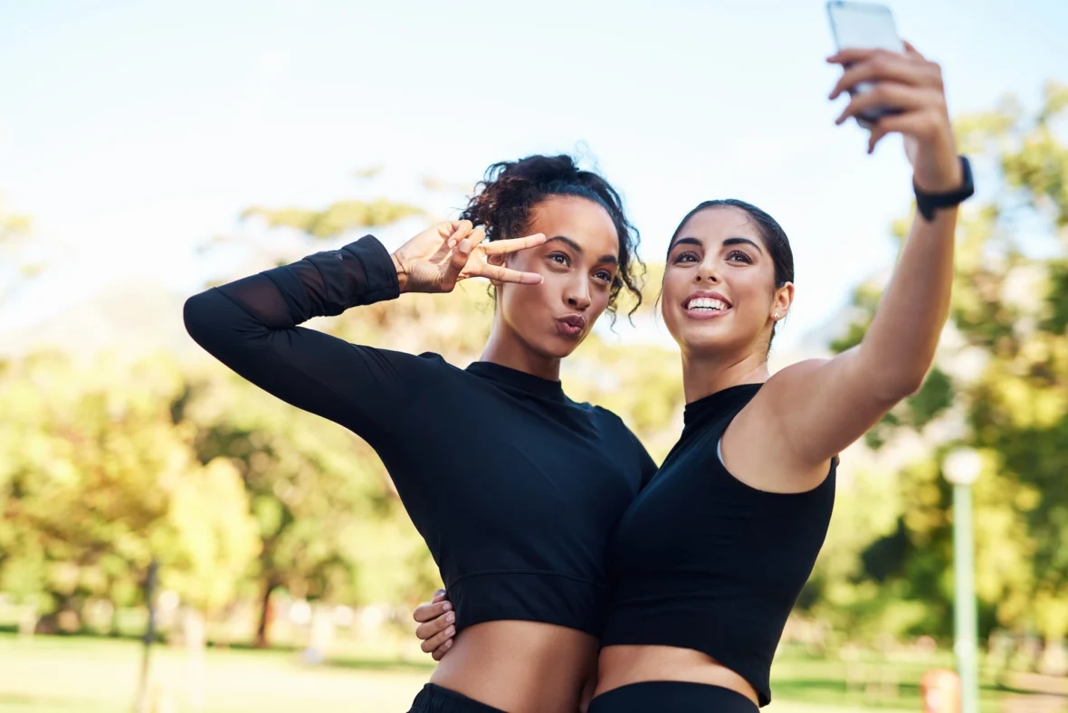 two young women in fitness gear pose for a selfie