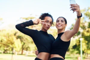 two young women in fitness gear pose for a selfie